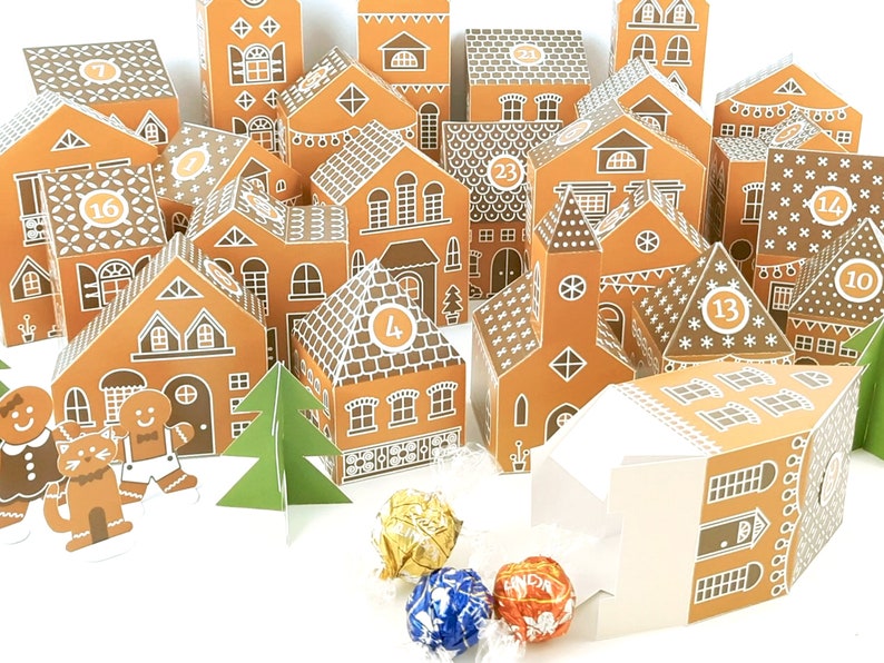 May include: A gingerbread house advent calendar with 24 numbered doors, each shaped like a small house. The houses are decorated with white icing and gingerbread details. There are also two gingerbread people and a small green Christmas tree.
