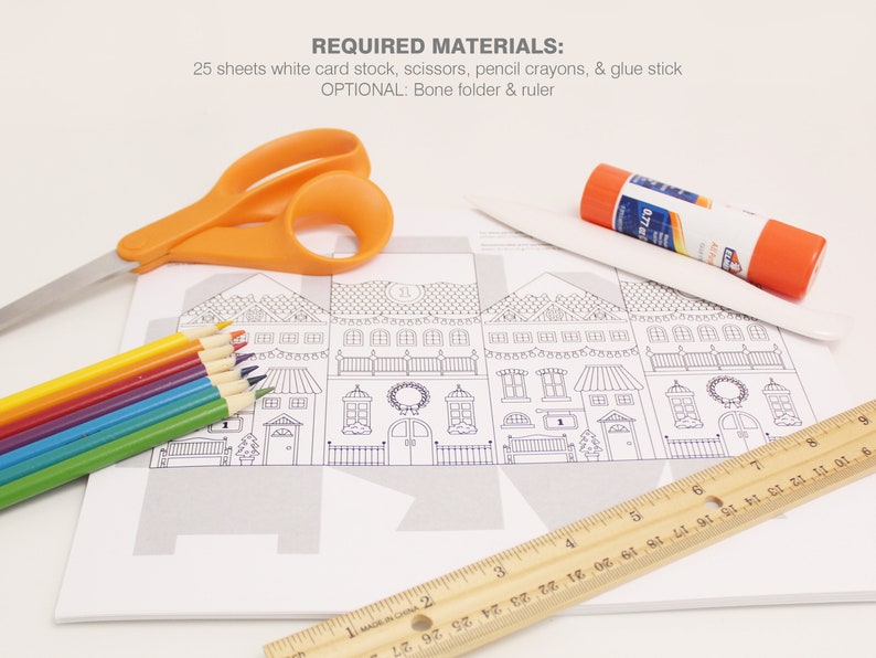 Image shows the materials required to make the advent calendar Christmas coloring houses: white card stock, scissors, glue stick, ruler and bone folder, and pencil crayons