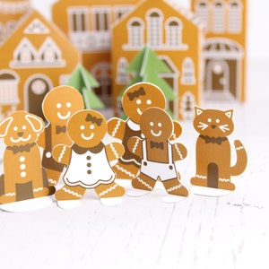 May include: A gingerbread family with a dog and cat standing in front of gingerbread houses. The gingerbread people are wearing festive attire, including a bow tie, a dress, and overalls. The dog and cat are also wearing bow ties.