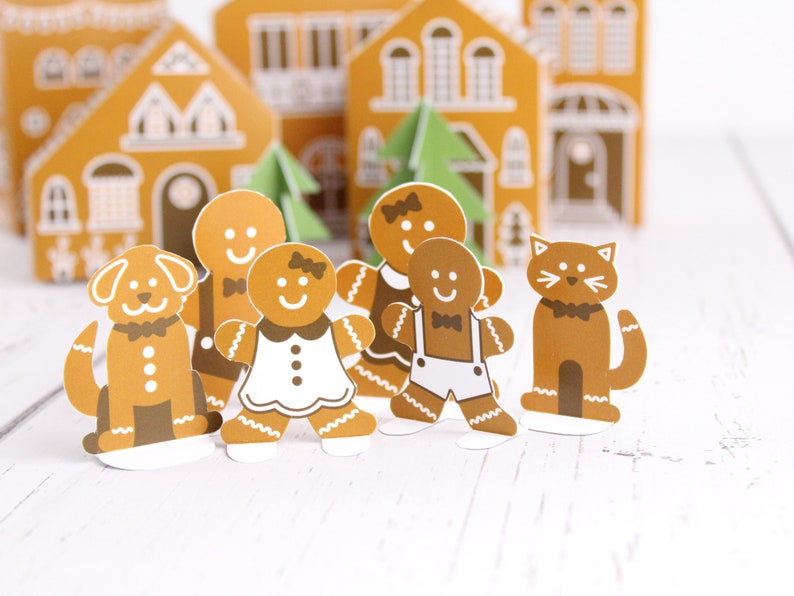 May include: A gingerbread family with a dog and cat standing in front of gingerbread houses. The gingerbread people are wearing festive attire, including a bow tie, a dress, and overalls. The dog and cat are also wearing bow ties.