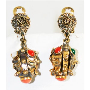 Puede incluir: Un par de pendientes colgantes de tono dorado con un dise&ntilde;o floral en la parte superior y un racimo de piedras redondas multicolores en la parte inferior.