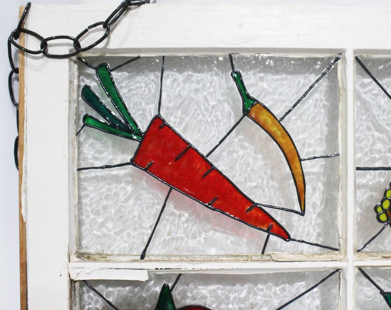 May include: A stained glass window panel featuring a red carrot and a yellow chilli pepper on a white background.