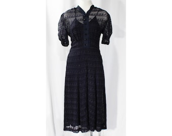May include: A navy blue lace dress with a button-up front and short sleeves. The dress has a fitted bodice and a flowing skirt.