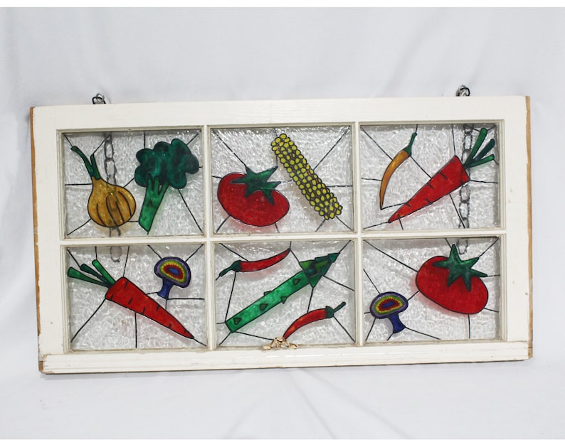 May include: A white window frame with nine panes of glass, each featuring a hand-painted vegetable design. The vegetables include carrots, onions, broccoli, tomatoes, peppers, corn, and mushrooms. The vegetables are painted in bright colours, including red, green, yellow, orange, and purple.