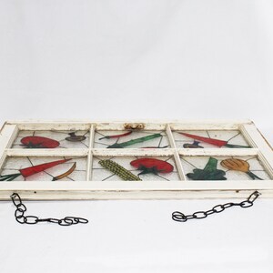 May include: A white painted window frame with a chain hanging from each side. The glass panes are painted with colourful vegetables, including tomatoes, carrots, corn, and peppers.