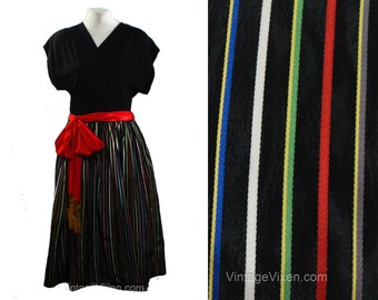 May include: A black vintage dress with a red sash and a multi-colored striped skirt. The skirt has vertical stripes of white, red, yellow, green, blue, and gray.