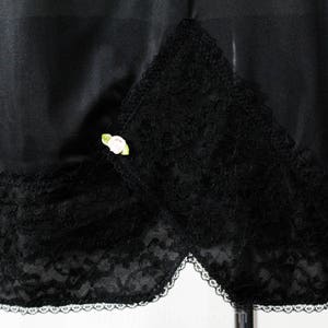May include: Black satin skirt with a lace trim and a small white flower embellishment.