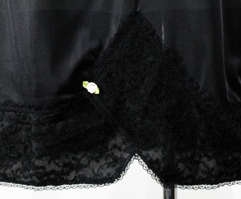 May include: Black satin skirt with a lace trim and a small white flower embellishment.