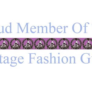 May include: A purple banner with the text "Proud Member Of The Vintage Fashion Guild" in blue letters. The banner is decorated with a repeating pattern of black and white logos.
