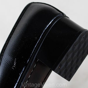 May include: Close-up of the black rubber sole of a black leather shoe. The sole has a textured pattern.