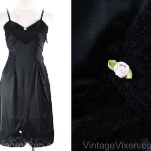 May include: Black slip with lace trim and a small white flower detail. The slip is made of a smooth, silky fabric.