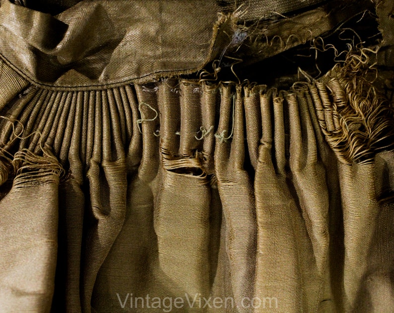 May include: Close-up of a section of vintage fabric in shades of gold and brown. The fabric is heavily textured with pleats and frayed edges, suggesting age and wear. The text "Vintage Vixen.com" is visible at the bottom.