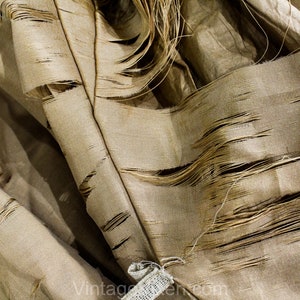 May include: Close-up of a tan fabric with a distressed, shredded design. The fabric has a textured appearance with visible threads and frayed edges, creating a vintage aesthetic. The fabric is likely used for upholstery or decorative purposes.