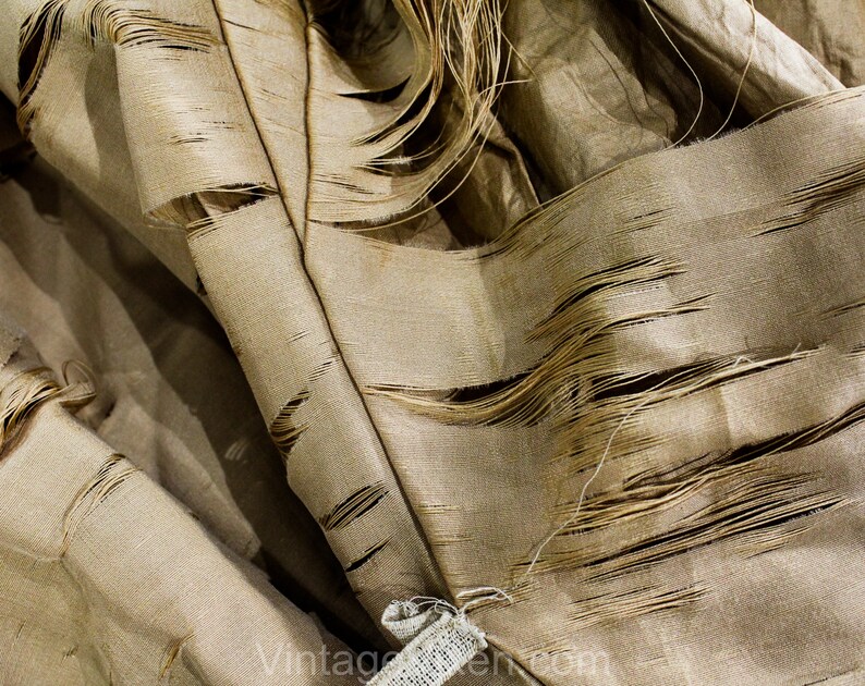 May include: Close-up of a tan fabric with a distressed, shredded design. The fabric has a textured appearance with visible threads and frayed edges, creating a vintage aesthetic. The fabric is likely used for upholstery or decorative purposes.
