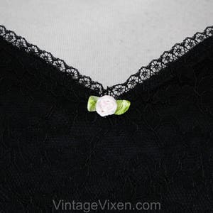May include: Black lace fabric with a small pink and green flower embellishment.