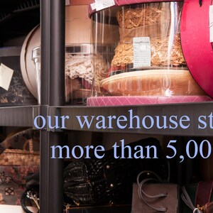 May include: A black metal shelving unit filled with various items, including hats, boxes, and bags. The text "our warehouse stores more than 5,000 items" is visible on the shelf.