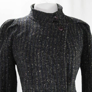 May include: A black and gold tweed jacket with a high collar and two button closures.