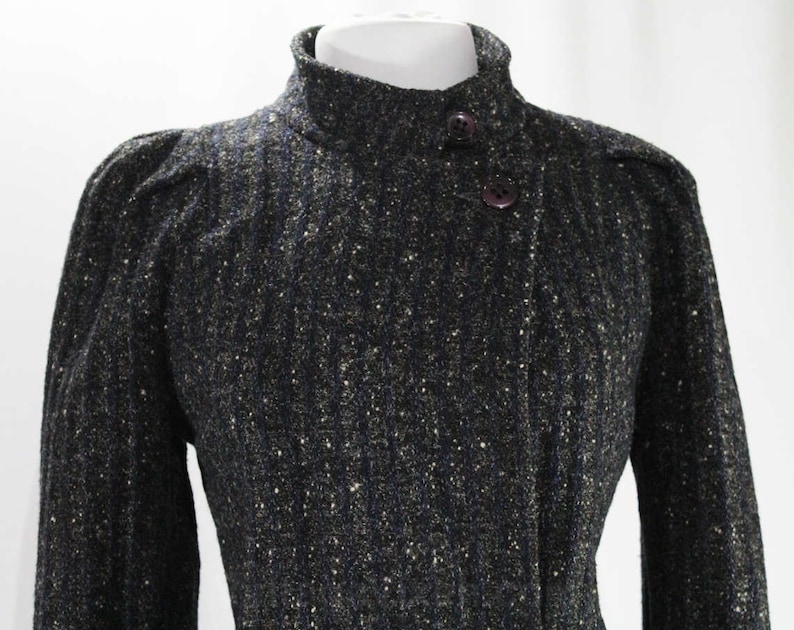 May include: A black and gold tweed jacket with a high collar and two button closures.