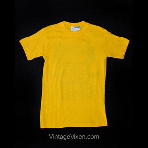 Puede incluir: Una camiseta de manga corta de color amarillo brillante con cuello redondo.