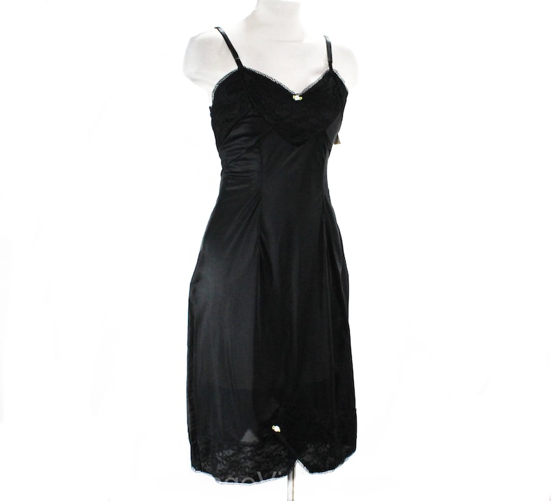 May include: Black slip dress with lace trim and adjustable straps. The dress is made of a smooth, silky fabric.