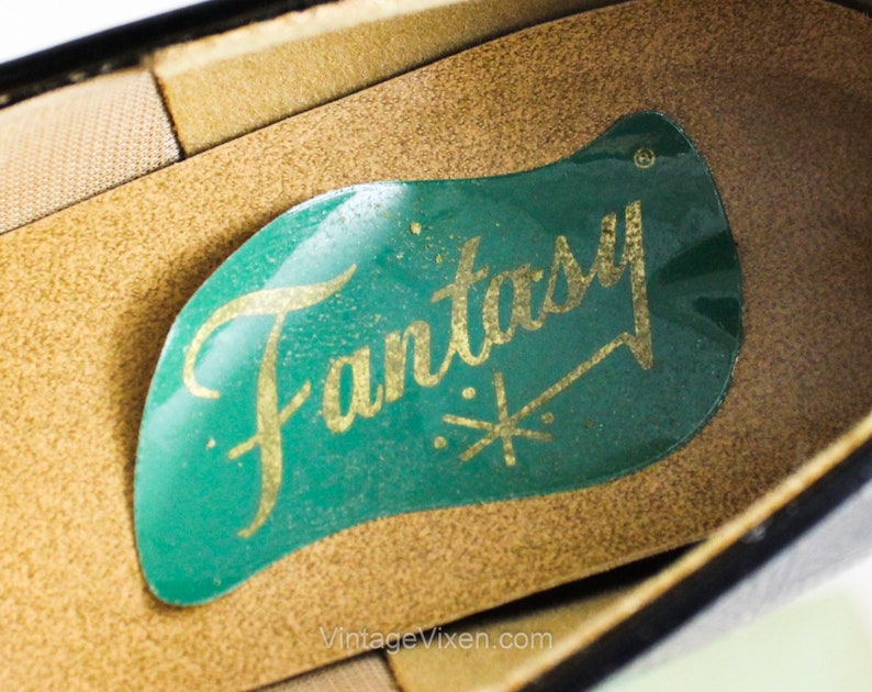 May include: Close-up of the inside of a black shoe with a green label that says "Fantasy" in gold lettering.