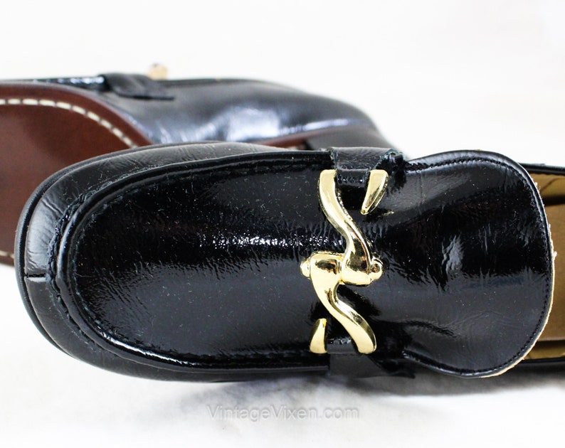 May include: Black leather loafers with a gold buckle. The loafers have a pointed toe and a low heel.
