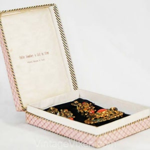 Puede incluir: Una caja de joyer&iacute;a abierta de rayas rosas y blancas con un interior de terciopelo negro. La caja contiene un conjunto de joyas de oro y coral. La caja tiene el texto "Italian Jewelry in Gold & Silver" impreso en el interior.