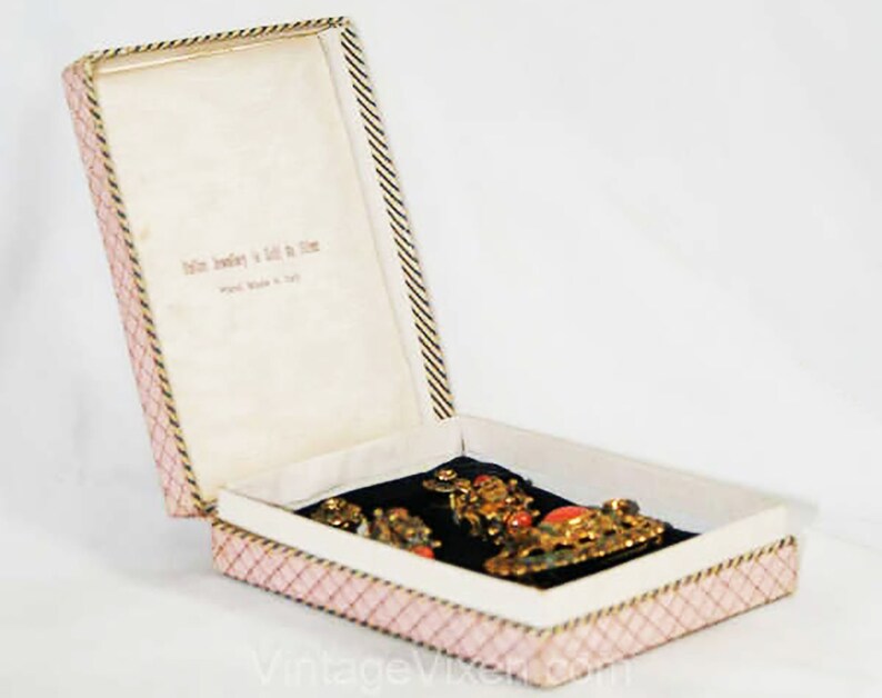 Puede incluir: Una caja de joyer&iacute;a abierta de rayas rosas y blancas con un interior de terciopelo negro. La caja contiene un conjunto de joyas de oro y coral. La caja tiene el texto "Italian Jewelry in Gold & Silver" impreso en el interior.