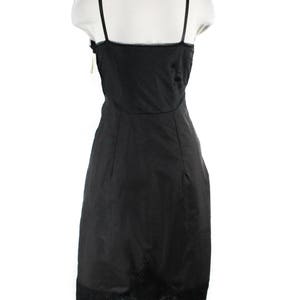 May include: Black slip dress with lace trim. The dress has thin straps and a fitted silhouette.