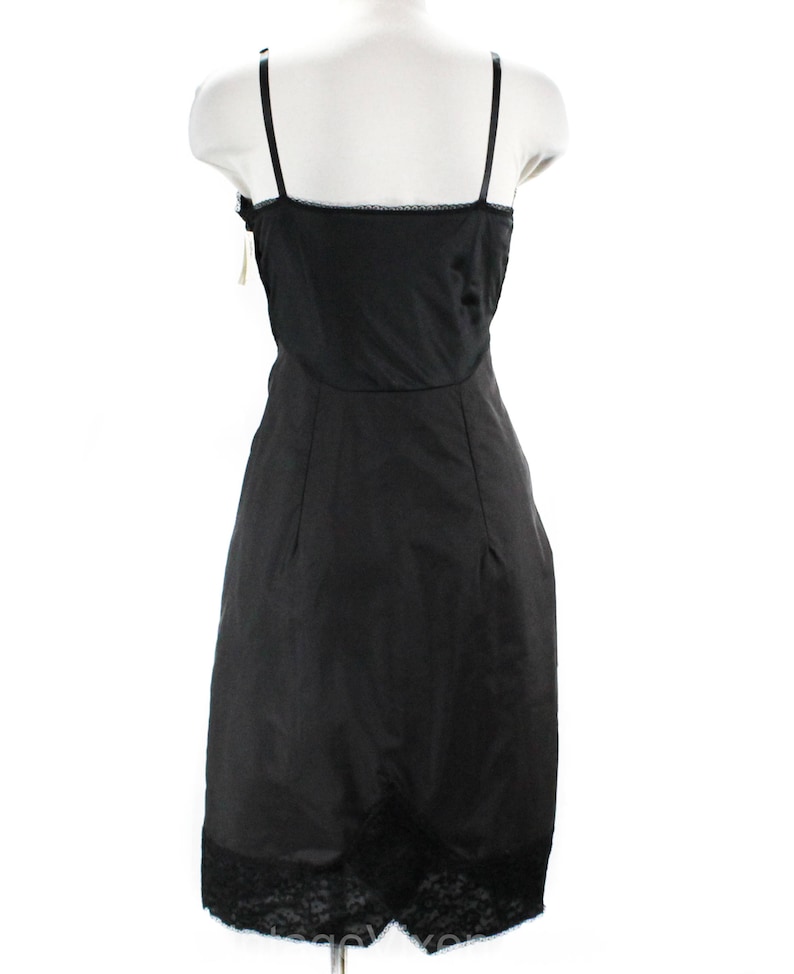 May include: Black slip dress with lace trim. The dress has thin straps and a fitted silhouette.