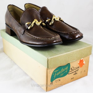 May include: Brown leather loafers with a gold buckle and a low heel. The shoes are in a box labeled "Fantasy" with the number 45 7274.