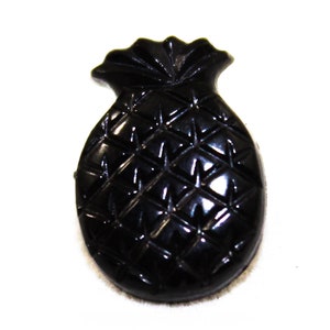 Könnte beinhalten: Ein schwarzer Ananas-Knopf aus Harz mit einer strukturierten Oberfläche.