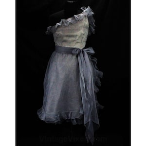 May include: A light blue one-shoulder dress with a ruffled neckline and a matching sash. The dress is made of a sheer fabric and has a flowing silhouette.