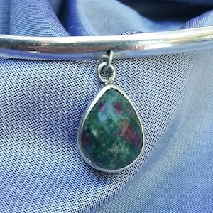 Peut inclure: Un bracelet en argent avec un pendentif en forme de larme en pierre verte et rouge.