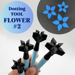 May include: A set of black dotting tools with flower-shaped tips and light blue handles. The image also shows blue flower designs and text that reads "Dotting TOOL FLOWER #2". These tools are likely used for art or craft projects.