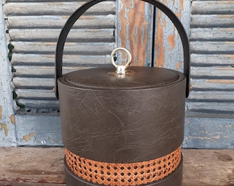 May include: A brown faux leather ice bucket with a woven wicker band and a gold handle.