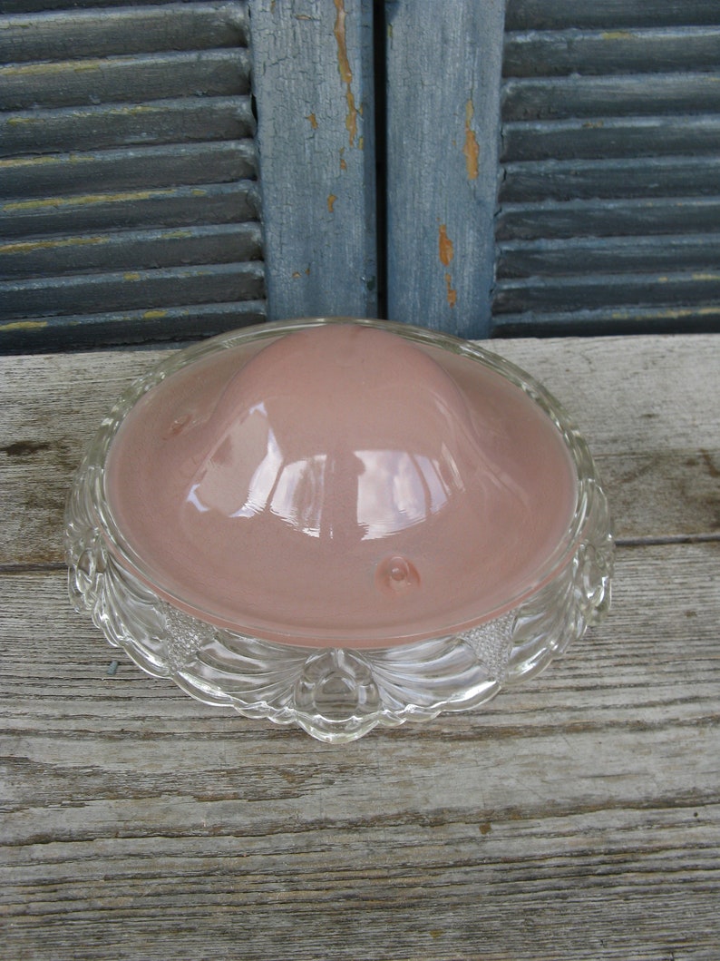 Puede incluir: Una l&aacute;mpara de techo de cristal rosa con un borde festoneado de cristal transparente.