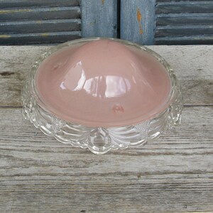 Puede incluir: Una l&aacute;mpara de techo vintage de vidrio con una pantalla de vidrio rosa y una base de vidrio transparente con un dise&ntilde;o decorativo.
