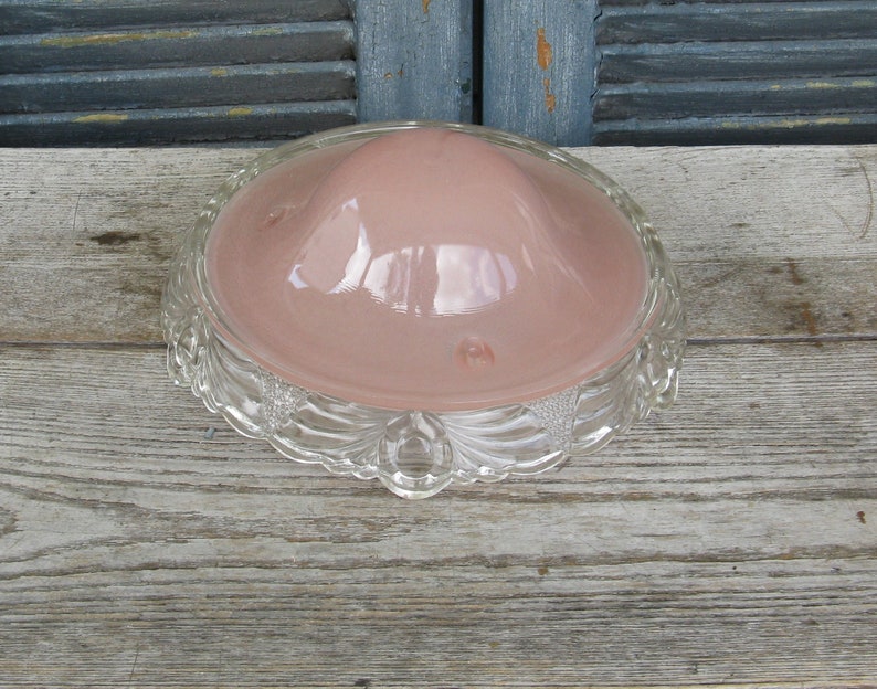 Puede incluir: Una l&aacute;mpara de techo vintage de vidrio con una pantalla de vidrio rosa y una base de vidrio transparente con un dise&ntilde;o decorativo.