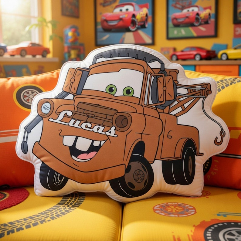 May include: A die-cut throw pillow shaped like the brown tow truck character Mater from the movie Cars. The character features green eyes, a wide smile with buck teeth, and the name Lucas printed in white script on the front hood.
