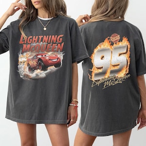 Op de afbeelding: Donkergrijs Lightning McQueen T-shirt. De voorkant heeft een rode cartoon raceauto met nummer 95 en de tekst "Lightning McQueen". De achterkant toont nummer 95 in vlammen, met de tekst "Lightning McQueen".