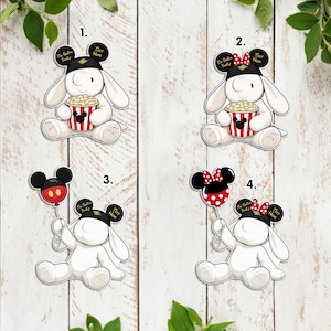 May include: Four cartoon stickers featuring a white bunny character with black Mickey Mouse ears and a black hat. The bunny holds a popcorn bucket, a Mickey Mouse balloon, or a Minnie Mouse balloon. The text "To Saire Family" is on the hat.