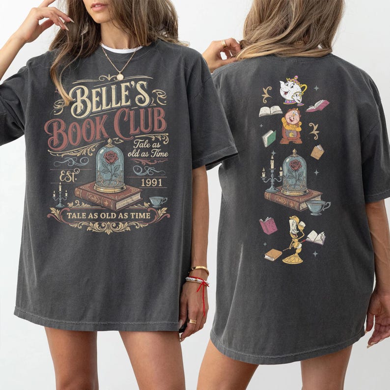 May include: Dark gray t-shirt featuring "Belle's Book Club" text and graphics from Beauty and the Beast. The front design includes a rose in a glass dome, books, and the text "Tale as old as Time". The back has additional character illustrations.