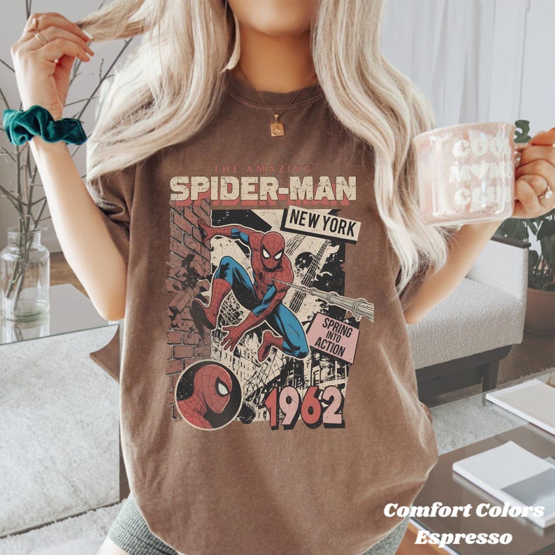 Op de afbeelding: Espresso-kleurig T-shirt met een vintage Spider-Man-afbeelding. Het ontwerp bevat de tekst "The Amazing Spider-Man New York" en "Spring into Action 1962". Onderdeel van de Comfort Colors collectie.