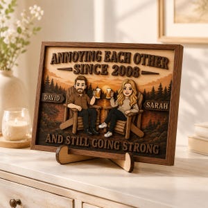 May include: A rectangular wooden framed sign featuring a cartoon illustration of a couple sitting in chairs holding beer mugs. The text reads ANNOYING EACH OTHER SINCE 2008, DAVID, SARAH, and AND STILL GOING STRONG against a sunset forest background.