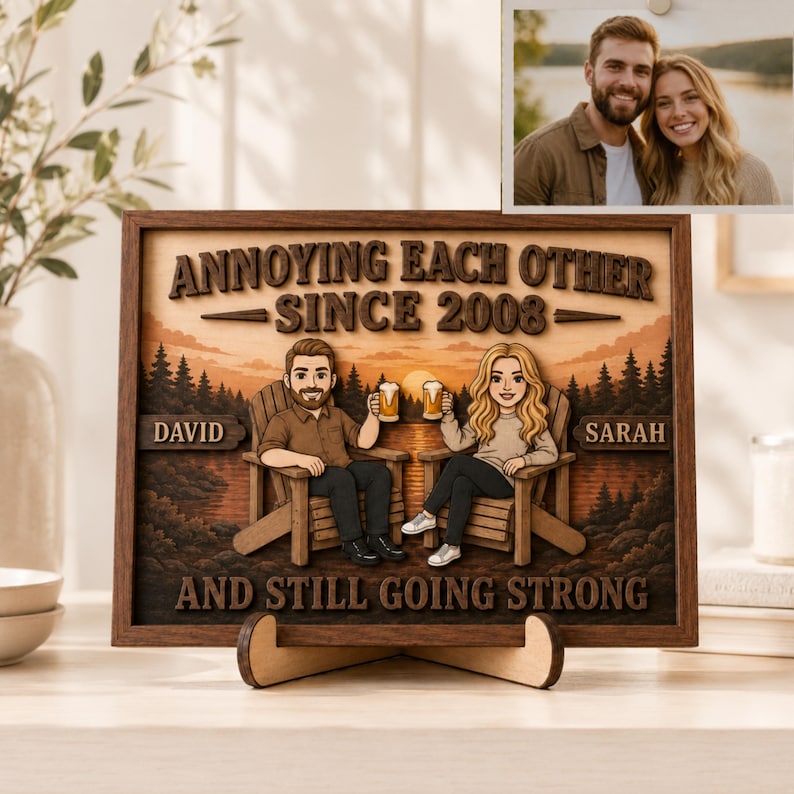 May include: A rectangular wooden wall art piece featuring a layered 3D design of a couple sitting in chairs with beer mugs. The text reads ANNOYING EACH OTHER SINCE 2008, DAVID, SARAH, and AND STILL GOING STRONG against a sunset forest background.