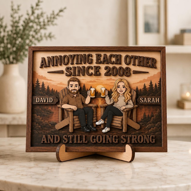 May include: A rectangular wooden wall art piece featuring a layered design of two people sitting in chairs holding beer mugs. The text reads ANNOYING EACH OTHER SINCE 2008, DAVID, SARAH, and AND STILL GOING STRONG against a sunset forest background.
