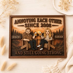 May include: A rectangular wooden wall sign featuring a layered 3D illustration of two people sitting in chairs with beer mugs. The text reads: ANNOYING EACH OTHER SINCE 2008, DAVID, SARAH, AND STILL GOING STRONG. The background depicts a sunset over a forest.