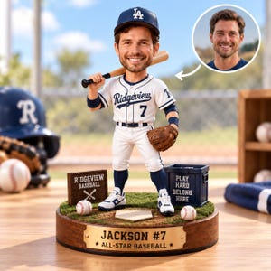 Könnte beinhalten: Eine personalisierte Wackelkopf-Figur eines Baseballspielers in weißer Uniform mit Ridgeview 7 auf der Brust, blauer Kappe und einem Baseballschläger. Der Sockel hat ein goldenes Schild mit der Aufschrift Jackson #7 All-Star Baseball.