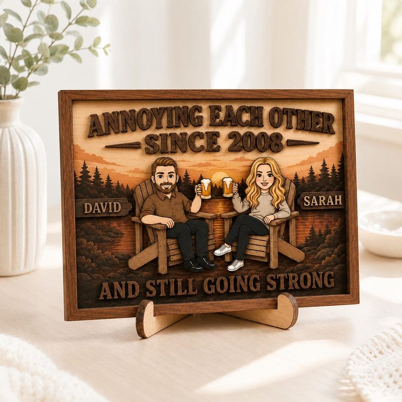 May include: A rectangular wooden framed sign featuring a layered illustration of two people sitting in chairs holding beer mugs. The text reads ANNOYING EACH OTHER SINCE 2008, DAVID, SARAH, and AND STILL GOING STRONG against a forest and sunset background.
